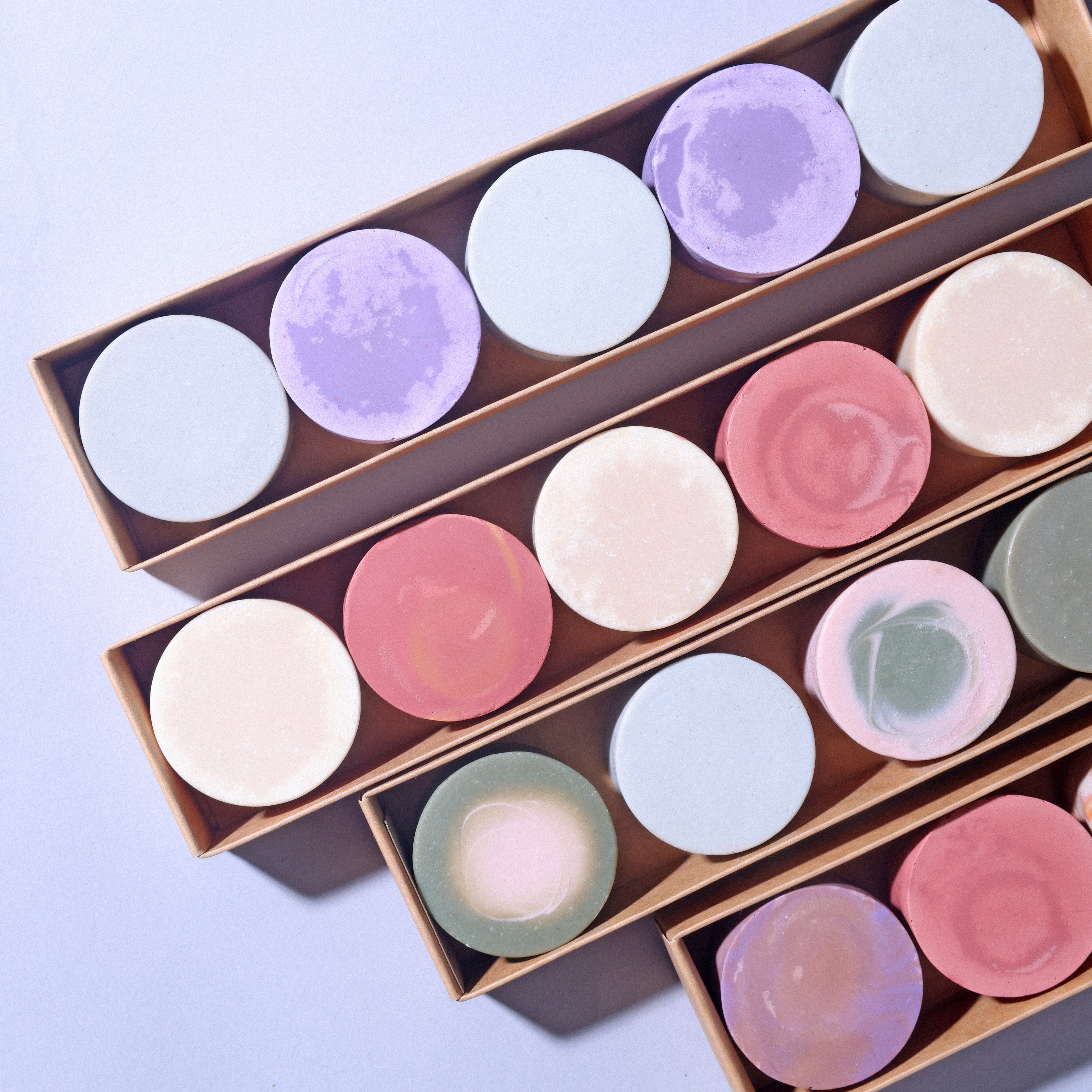 Colorful round artisan soaps with swirling designs in a rectangular gift box